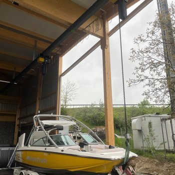 A boat is lifted from the boat trailer with chain hoists