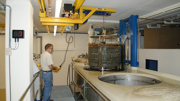 Crane system lifts metal container out of basin