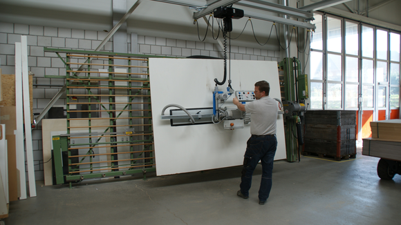 Wooden panel is transported from the lift truck to the vertical saw with a vacuum handling system