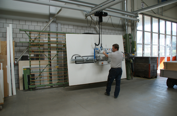 Wooden panel is transported from the lift truck to the vertical saw with a vacuum handling system