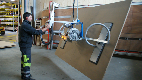 A large wooden panel is lifted by the forklift, tilted by 90° and moved to the vertical saw for cutting to size