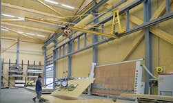 In a carpentry workshop, wooden boards are transported by means of a crane system