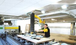 Wooden boards are transported in a carpentry workshop by means of a slewing crane