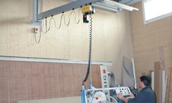 Wall-mounted slewing crane with vacuum lifter for wooden panels Slewing crane in use in wood processing for moving panels