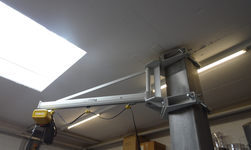 Working crane with electric chain hoist attached to concrete column