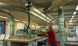 Vacuum handling system GH In a carpentry workshop, wooden boards are lifted onto the sawing machine by means of a vacuum lifter.